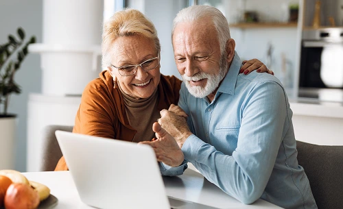 A old couple watching something on the laptop