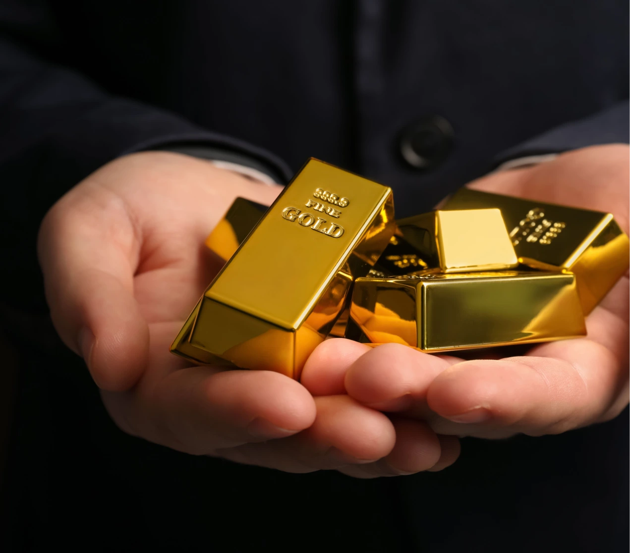 A person wearing black quote holding a gold bars