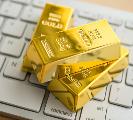 Gold bars on white keyboard computer background. Gold commodity trading market online investment concept. Digital technology for safe haven asset trading.