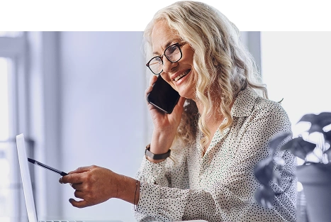 Smiling woman talking on the phone while working on a laptop