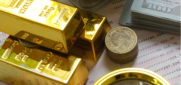 Gold bars, coins, and cash placed on financial documents