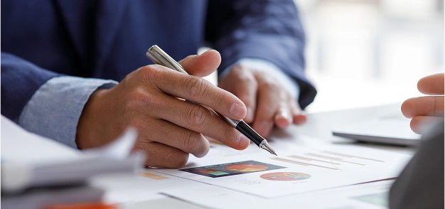 Person pointing at charts on a printed financial report